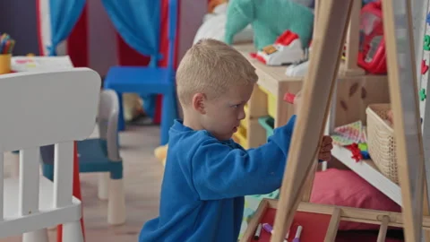 Boy drawing on a chalkboard with his hand and pink chalk in a playroom buil.. Stock Footage 339257469