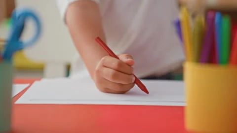 Boy drawing a circle with a red crayon, hand on paper, sitting at a classro.. Stock Footage 337373379
