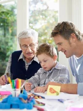 Boy Drawing With Crayons With Father And Grandfather Stock Photos