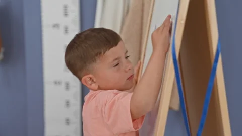 Boy drawing on easel with marker, right hand on whiteboard in studio; conce.. Stock Footage 339161095