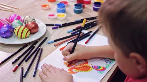 A boy is drawing an Easter drawing with pencils on a sheet of paper Stock Footage 172328649