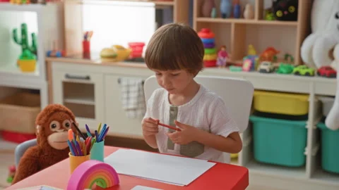 Boy drawing on paper with a pencil, hands holding the pencil at play table .. Stock Footage 339206272