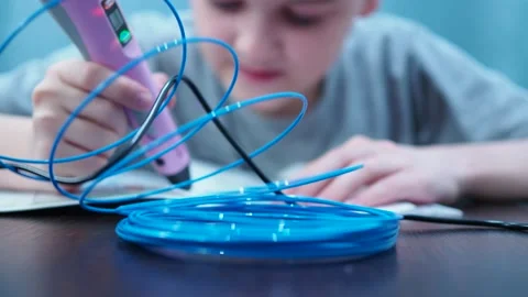 The boy draws with a 3D pen. the boy is out of focus, focus on the wire for the Stock Footage 146389005