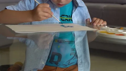 A boy draws with a brush on a glass table Video stock 168074274