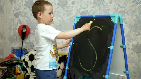 The boy draws on the chalkboard for writing chalks Stock Footage 76000398