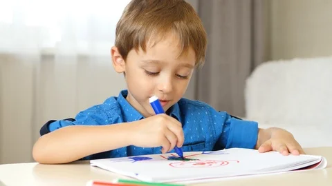 The boy draws with colored markers, imagining an unknown hero. Happy childhood Stock Footage 116396036