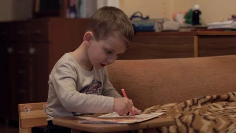 Boy draws a coloring book on the table Stock Footage 125177282