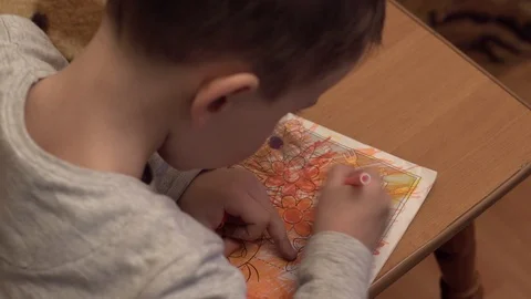 Boy draws a coloring book on the table Stock Footage 125177284