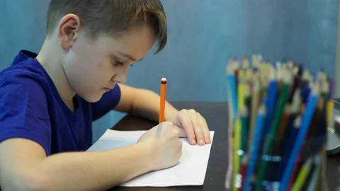 The boy draws a drawing on paper with colored pencils Stock Footage 145419082
