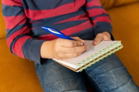 Boy draws in a notebook. Homework. Development of creativity in a child. 库存照片