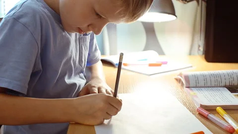 The boy draws on a sheet of paper and erases the drawn. Video stock 95654744