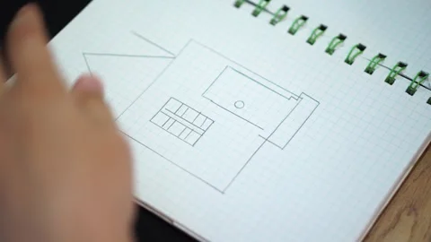 Boy draws simple drawing of house with pencil and ruler in squared notebook. han Stock Footage 307121736