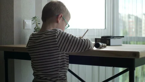 Boy draws sitting at the table by the window Stock Footage 98169176