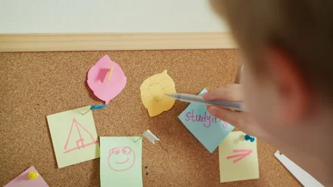 Boy draws sun on piece of colored paper in shape of leaf Stock Footage 248745155