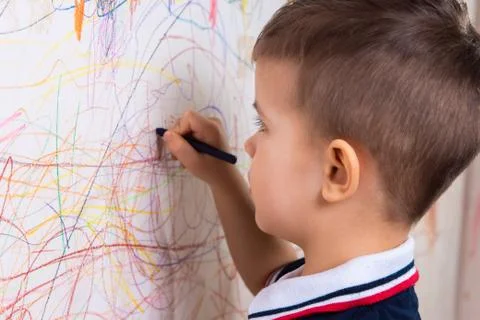 Boy draws on the wall with colored chalk. The child is engaged in creativity  Stock Photos