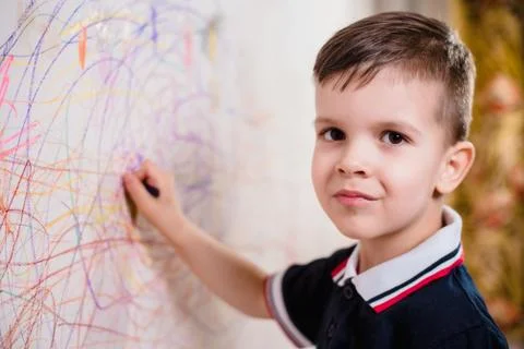 Boy draws on the wall with colored chalk. The child is engaged in creativity  Stock Photos