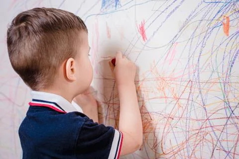 Boy draws on the wall with colored chalk. The child is engaged in creativity  Stock Photos