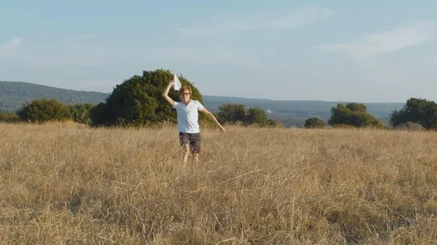 Boy dreaming to become pilot throwing paper planes on field. Child playing with Stock Footage 129423516