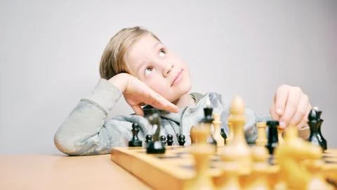 Boy dreaming while playing chess. Caucasian child thinks while playing chess Stock Photos