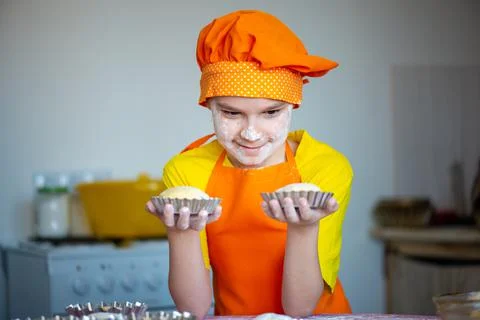 A boy dressed as a chef prepares Easter cakes in the kitchen Stock Photos