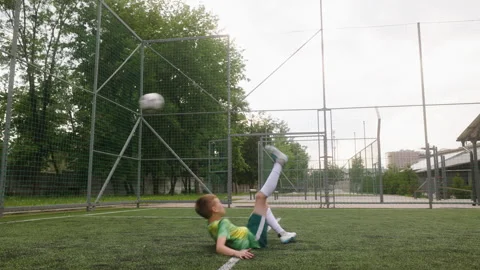 The boy dressed in football uniform is practicing on a mini football stadium Stock Footage 242597185