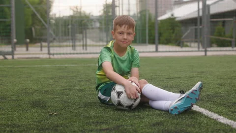 The boy dressed in football uniform is practicing on a mini football stadium. A Stock Footage 242598274