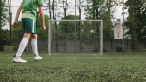 The boy dressed in football uniform is practicing on a mini football stadium. A Stock Footage 242598474