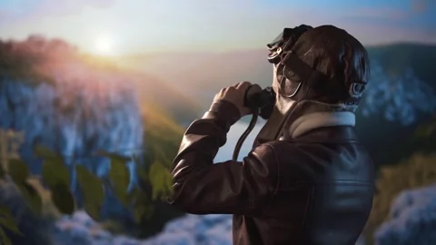 Boy dressed as old pilot looking through binoculars against valley background. 스톡 동영상 310264427
