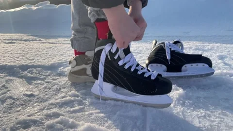 Boy dressing and tying skates for ice skating, winter sports, ice rink, skating Stock Footage 238595024