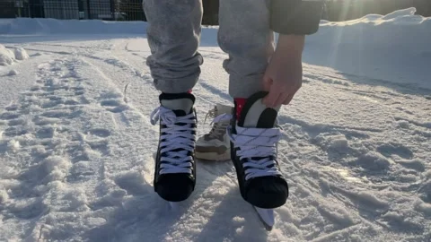 Boy dressing and tying skates for ice skating, winter sports, ice rink, skating Stock Footage 238595188