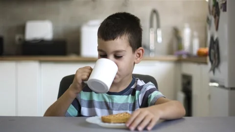 Boy drinking milk and eating cookies at table, slow motion Stock Footage 342239095