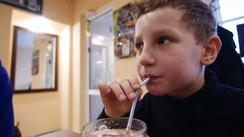A boy is drinking a milkshake through a straw, close-up Vidéo 94369122