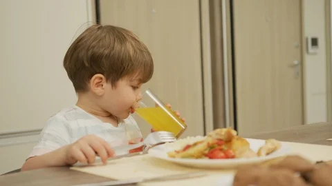 Boy drinking orange juice and talking Stock Footage 100001202