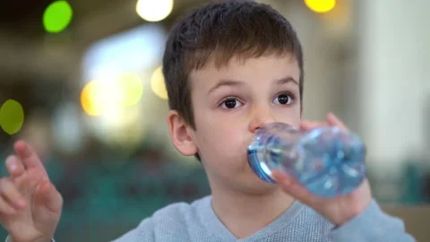 Boy drinking from plastic bottle of water in fast food restaurant. Vídeos de archivo 194577534