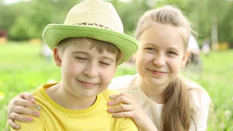 The boy is drinking water from the bottle.The smiling sister hugs her brother.  Stock Footage 76497465
