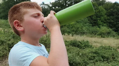 Boy drinking water from a reusable bottle on mountain Stock Footage 139298377
