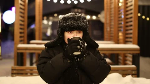 The boy drinks a hot drink at night on the street in winter, new year's fair Stock Footage 229835954