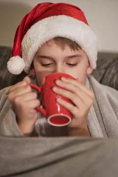 Boy drinks a hot drink wrapped in blanket. Holidays at home, Christmas mood. Stock Photos