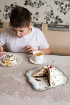 Boy drinks tea with cake at  table Stock Photos