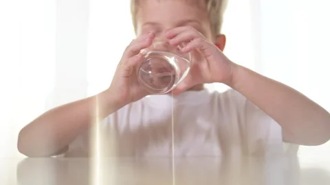 Boy drinks water from a glass in the kitchen. liquid healthy drink beverage Video stock 319475562