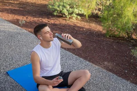 A boy drinks water while exercising outdoors, concept of hydration in sport Stock Photos