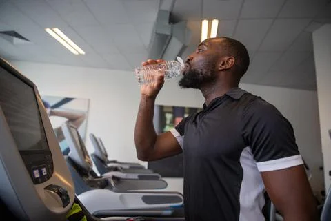 A boy drinks water while training in the gym, concept of hydration in sport Stock Photos