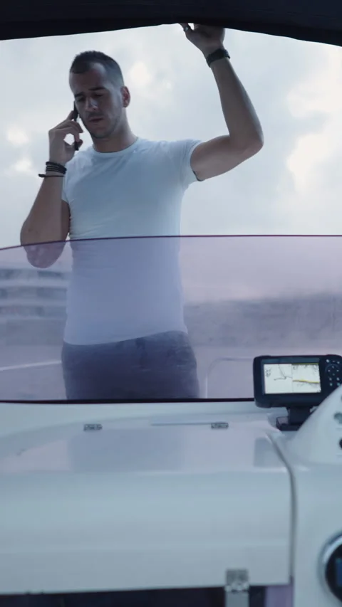 A boy drives a boat while his friend talks on the phone Video stock 264926208