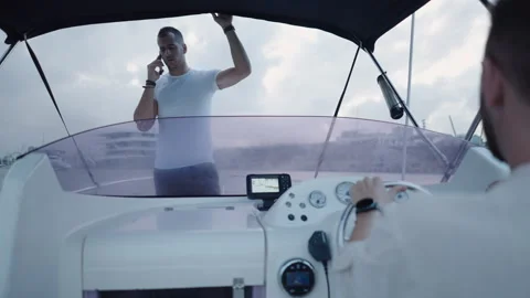 A boy drives a boat while his friend talks on the phone Stock Footage 265909097