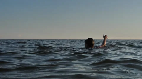 The boy drowning in the sea with his hands showing help Stock Footage 137221162