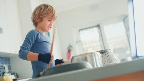 Boy Drumming in the kitchen using sticks and pots Stock Footage 279244912