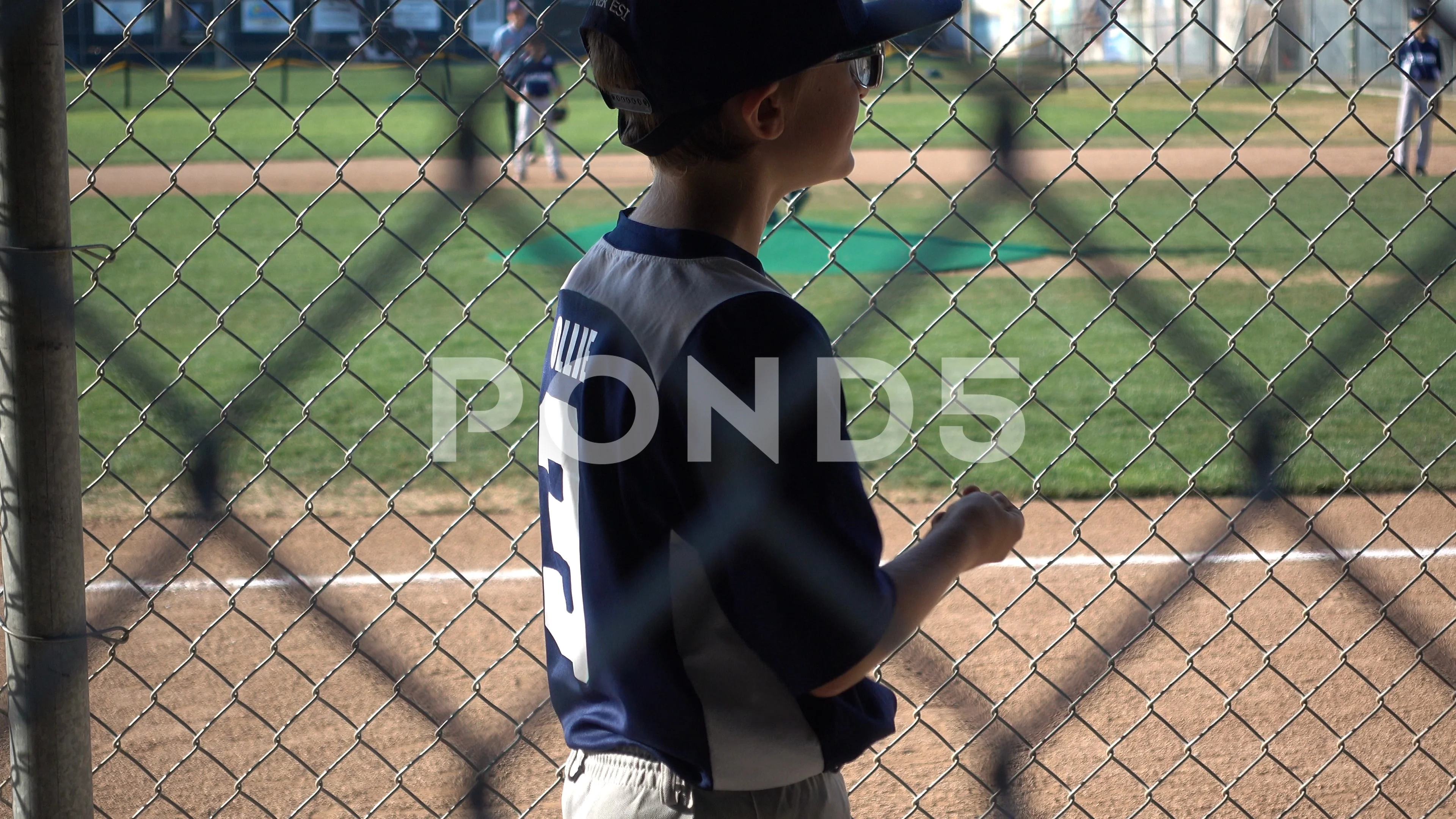 Youth Baseball Player Behind The Dugout Fence During A Game In