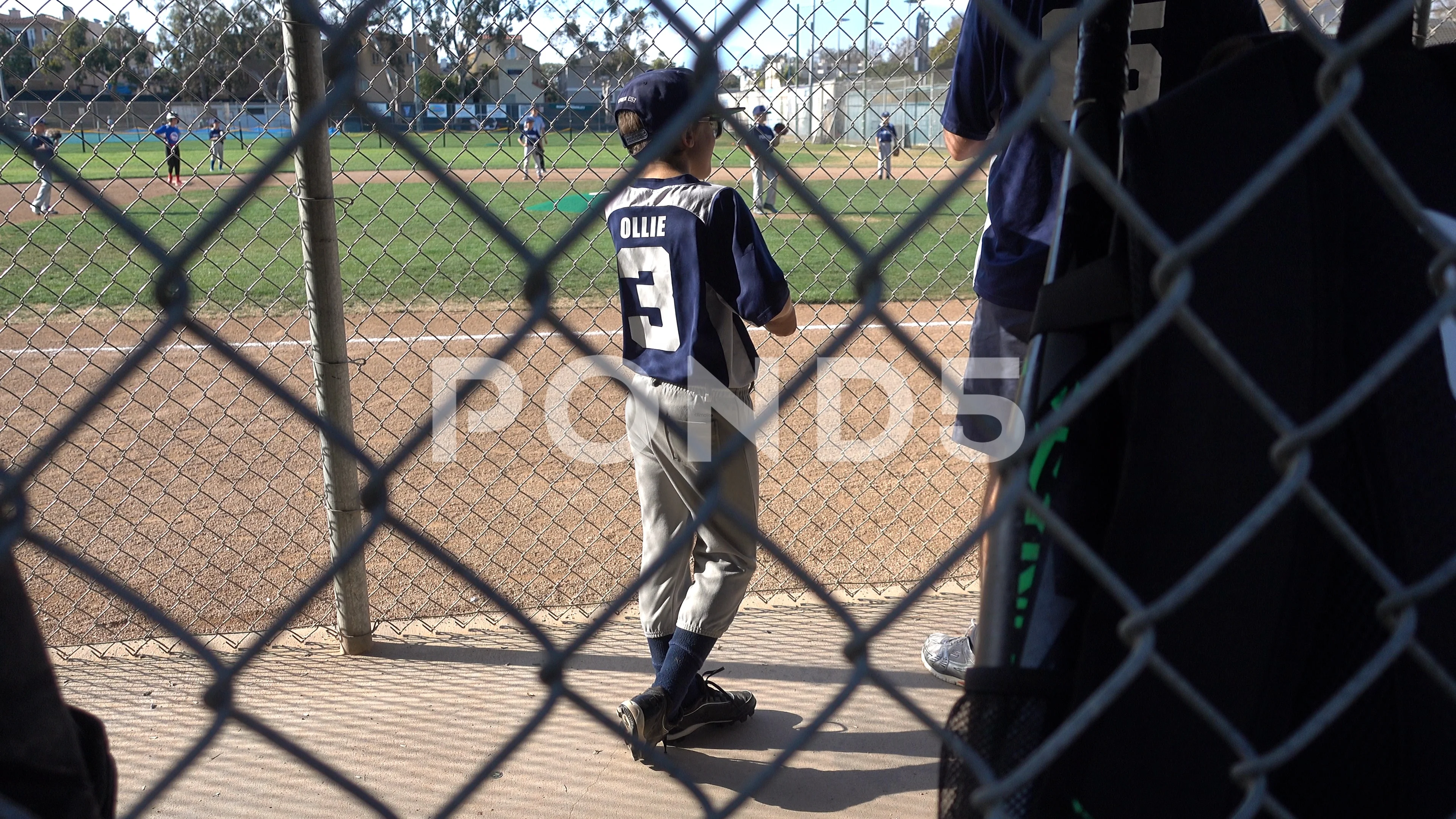 Youth Baseball Player Behind The Dugout Fence During A Game In