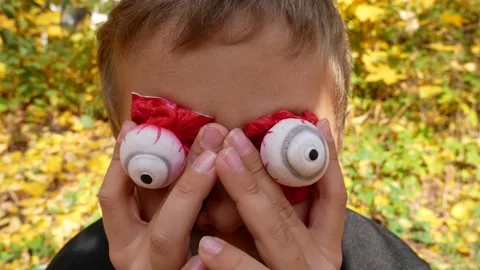 A boy during Halloween puts artificial scary bulging eyes on himself Stock Footage 163232723