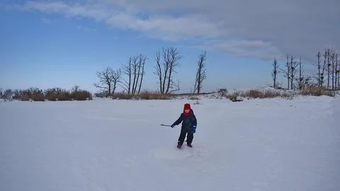 A boy during a winter walk to a small island in a lake Stock Photos